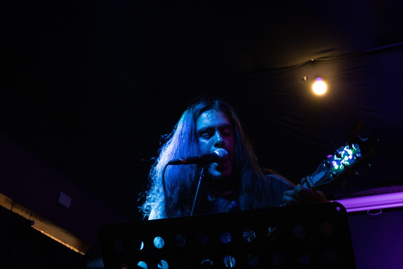 Vocalista de Krohma frente al micrófono, luz cálida, La Esquina Rosada