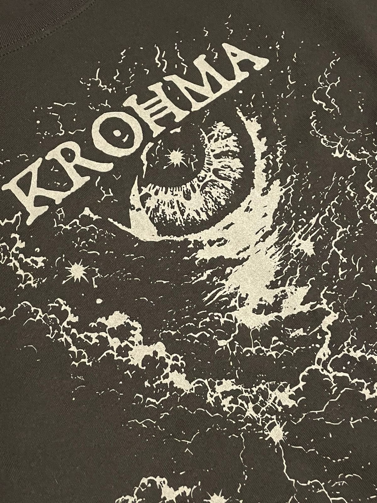 Detalle del logo KROHMA junto al ojo y la luna